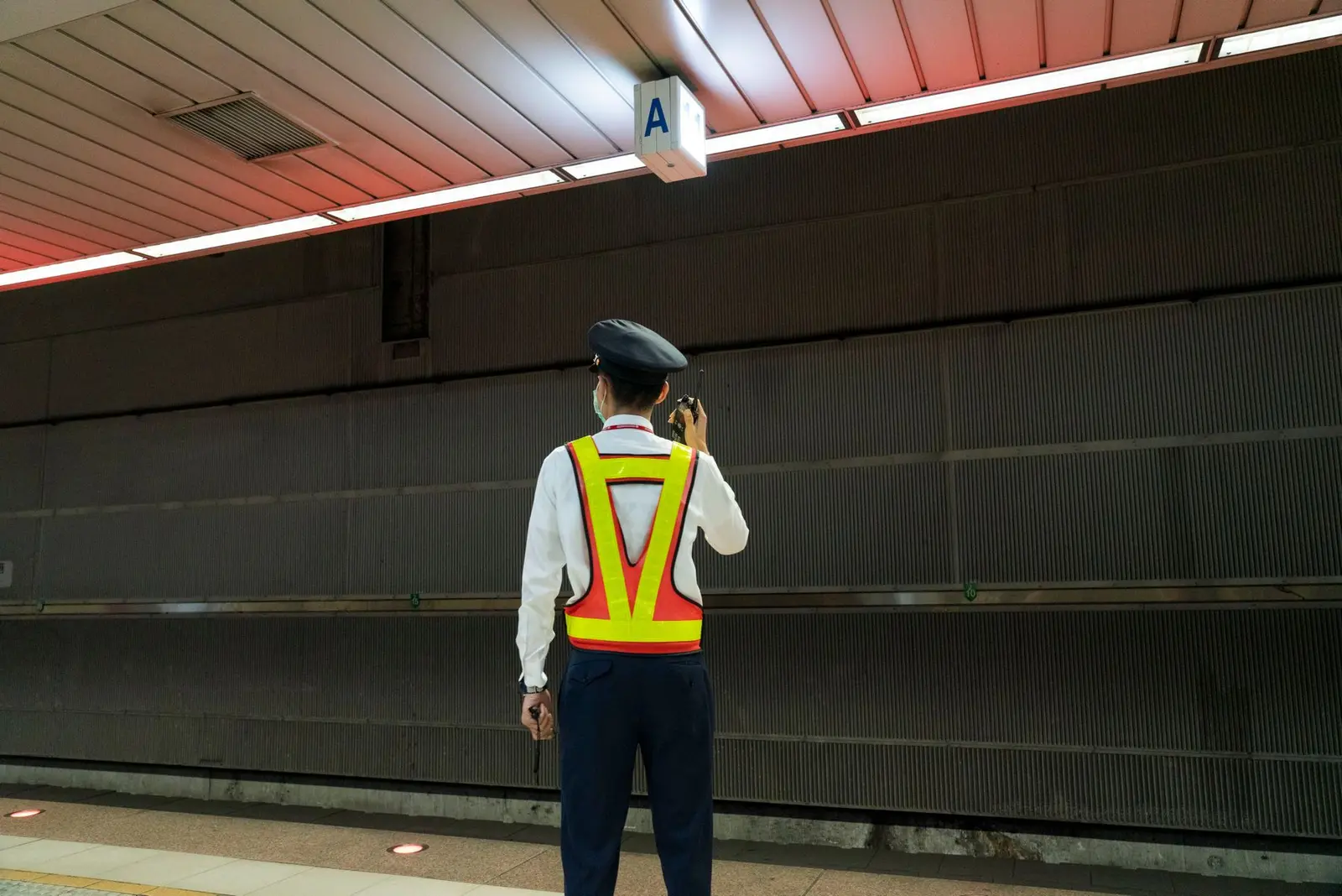 A security guard in a high-visibility vest using a radio