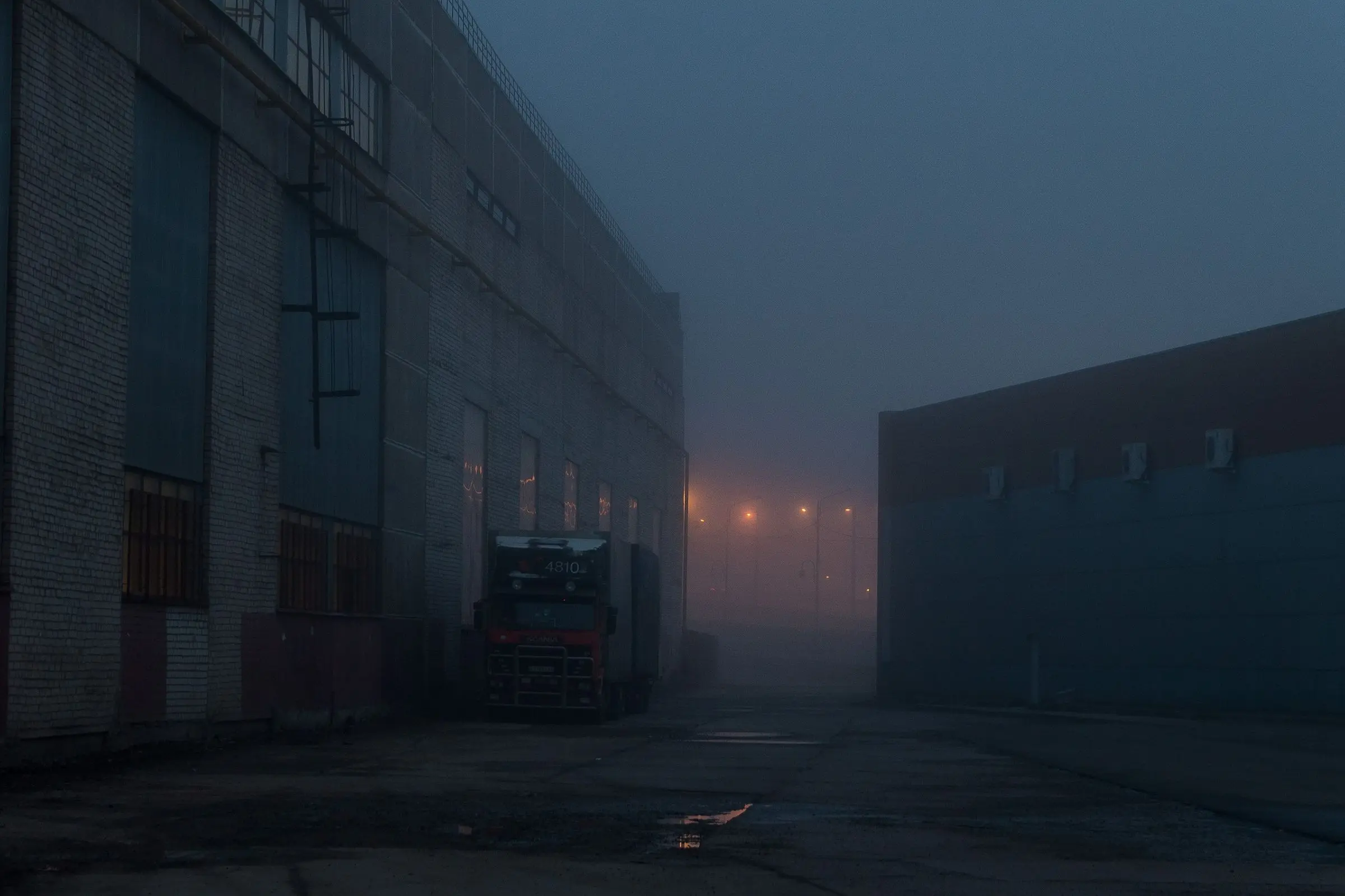 A warehouse yard in fog at night